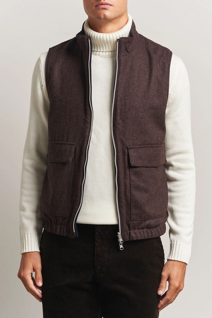 Homme portant un gilet en laine reversible marron avec col roulé blanc et fermeture à double zip.