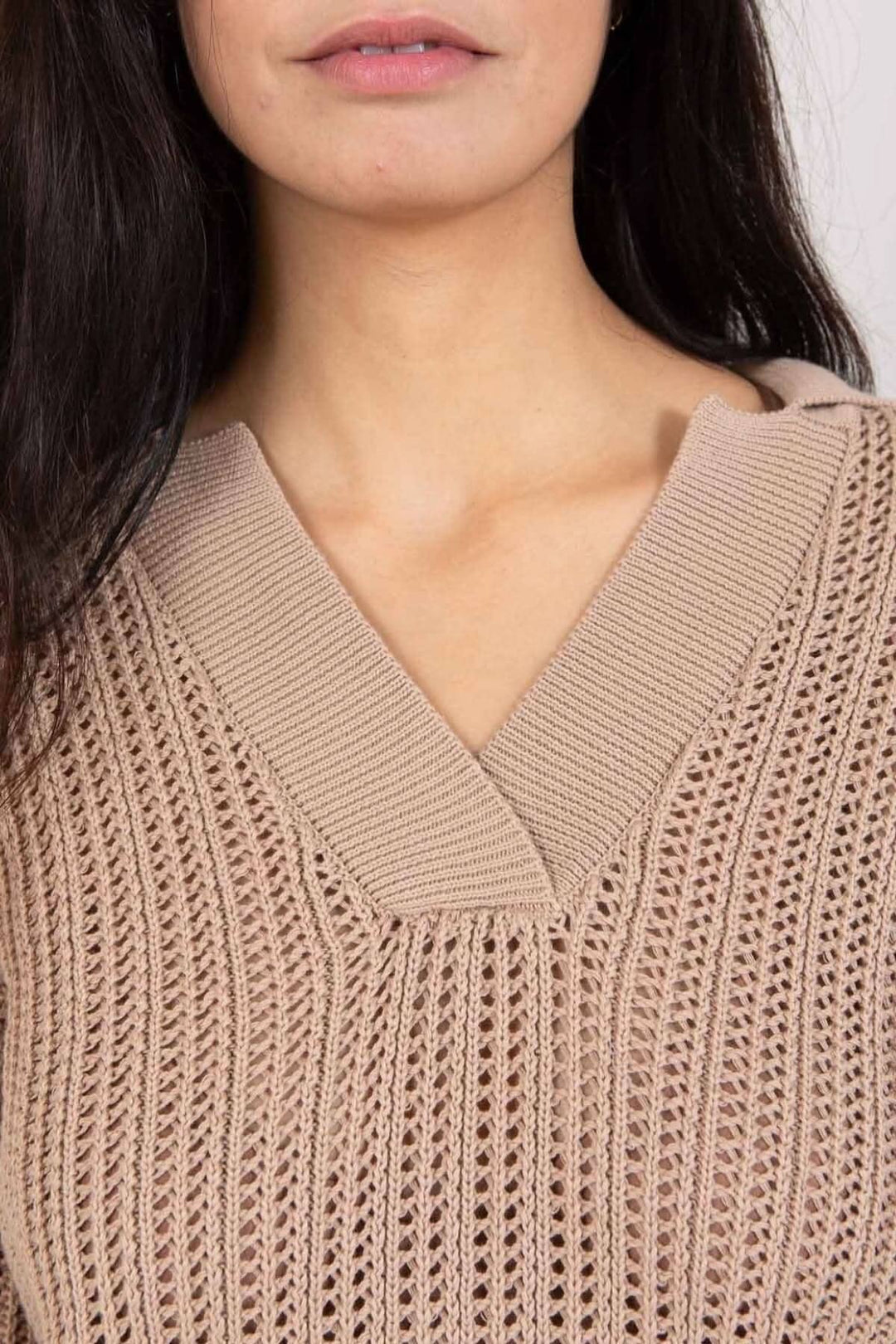 Détail du col en V d'un chandail maille ouverte, mettant en valeur sa texture et son design élégant.