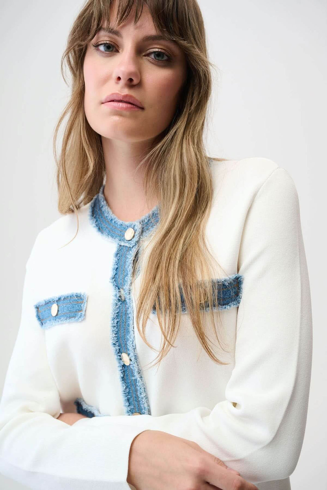 Femme portant un cardigan élégant avec détails denim effiloché et boutons métalliques. Tendance et original, coupe droite raffinée.