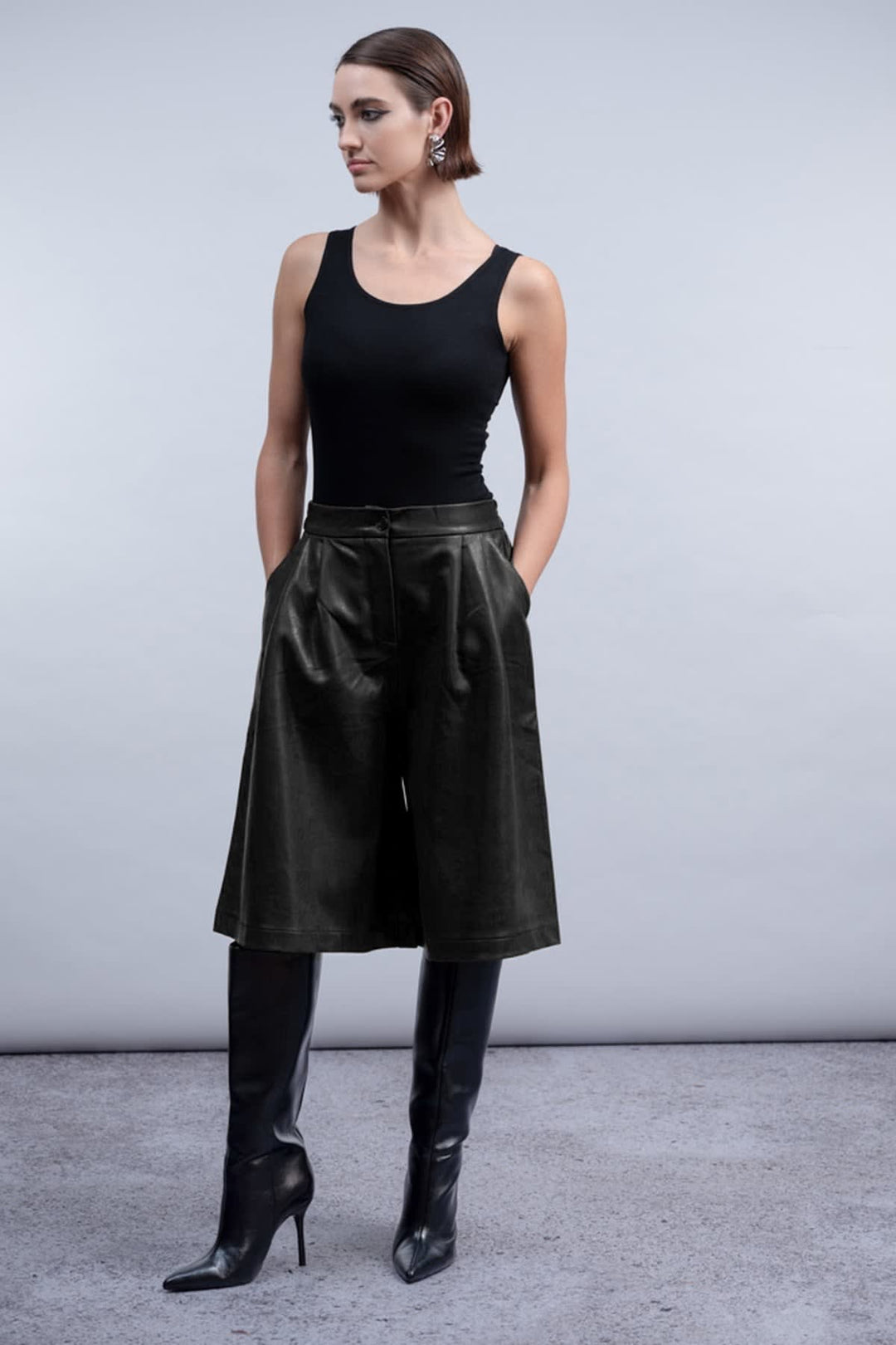 Side view of the Haako black faux-leather culotte skirt for women with an exposed zipper - Valérie Simon