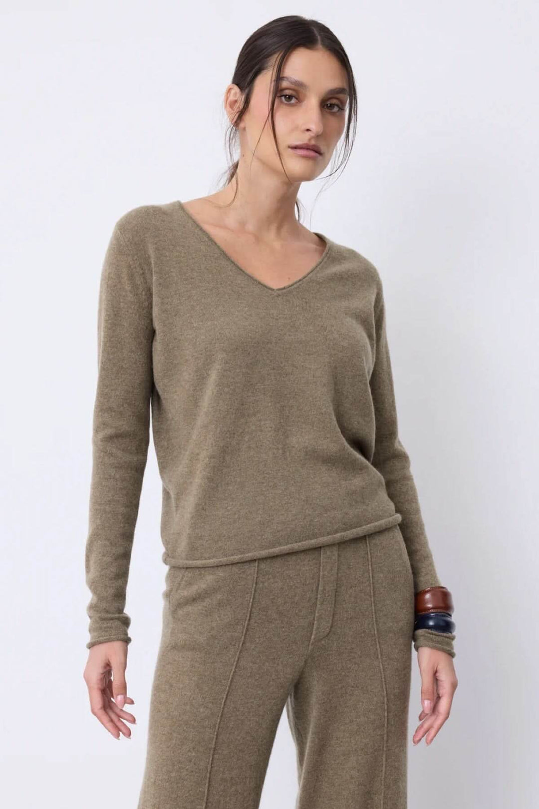 Chandail à manches longues vert olive avec encolure en V, style simple et élégant, porté avec un pantalon assorti.