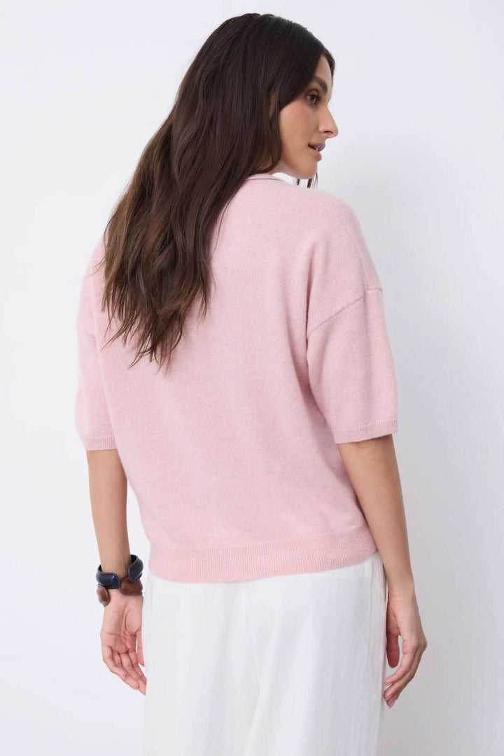 Femme portant un polo à manches courtes rose, vue arrière, avec une coupe droite et confortable.