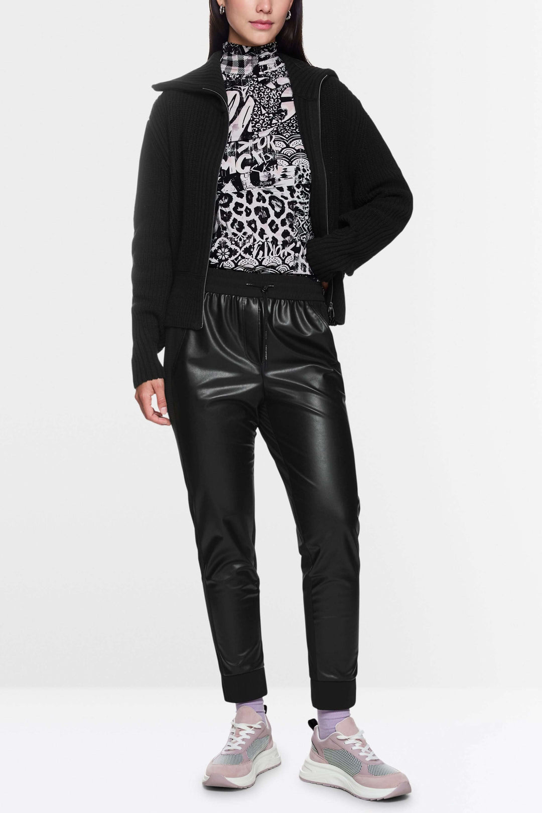 Femme portant un pantalon effet cuir noir avec taille élastique et pull, associée à des baskets tendance.