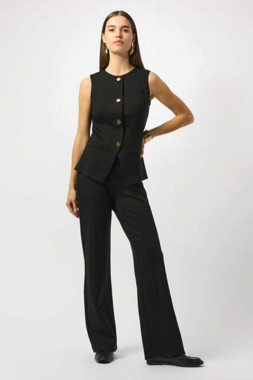 Veste boutonnée sans manches noire avec coupe cintrée et boutons dorés, portée avec un pantalon noir chic.