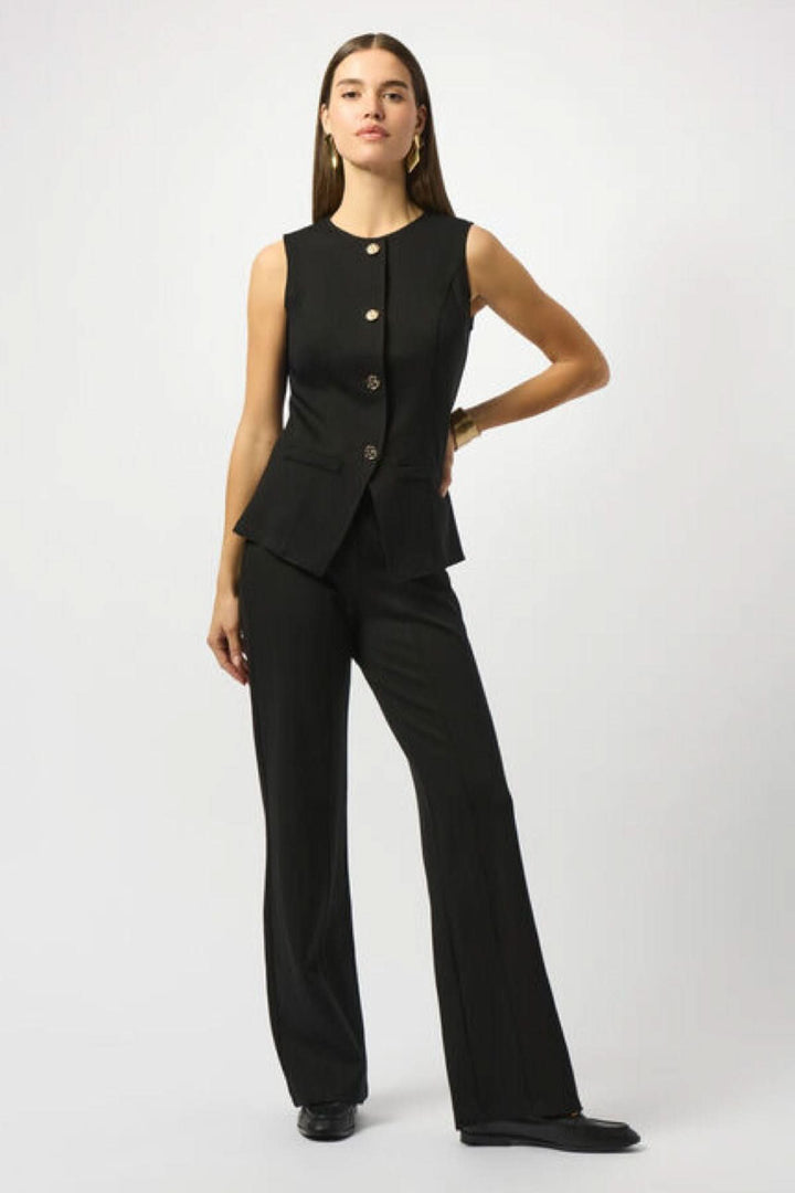 Veste boutonnée sans manches noire avec coupe cintrée et boutons dorés, portée avec un pantalon noir chic.