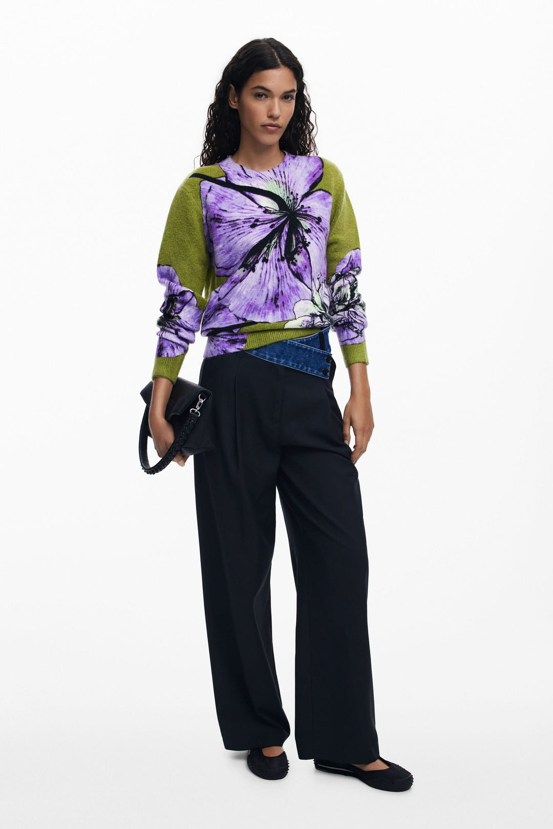 Chandail floral à col rond, imprimé oversize aux teintes vibrantes, porté avec pantalon noir.