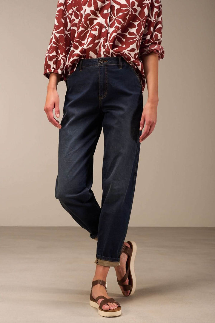 Jean à coupe décontractée denim foncé avec revers, porté avec un chemisier à fleurs et des sandales.