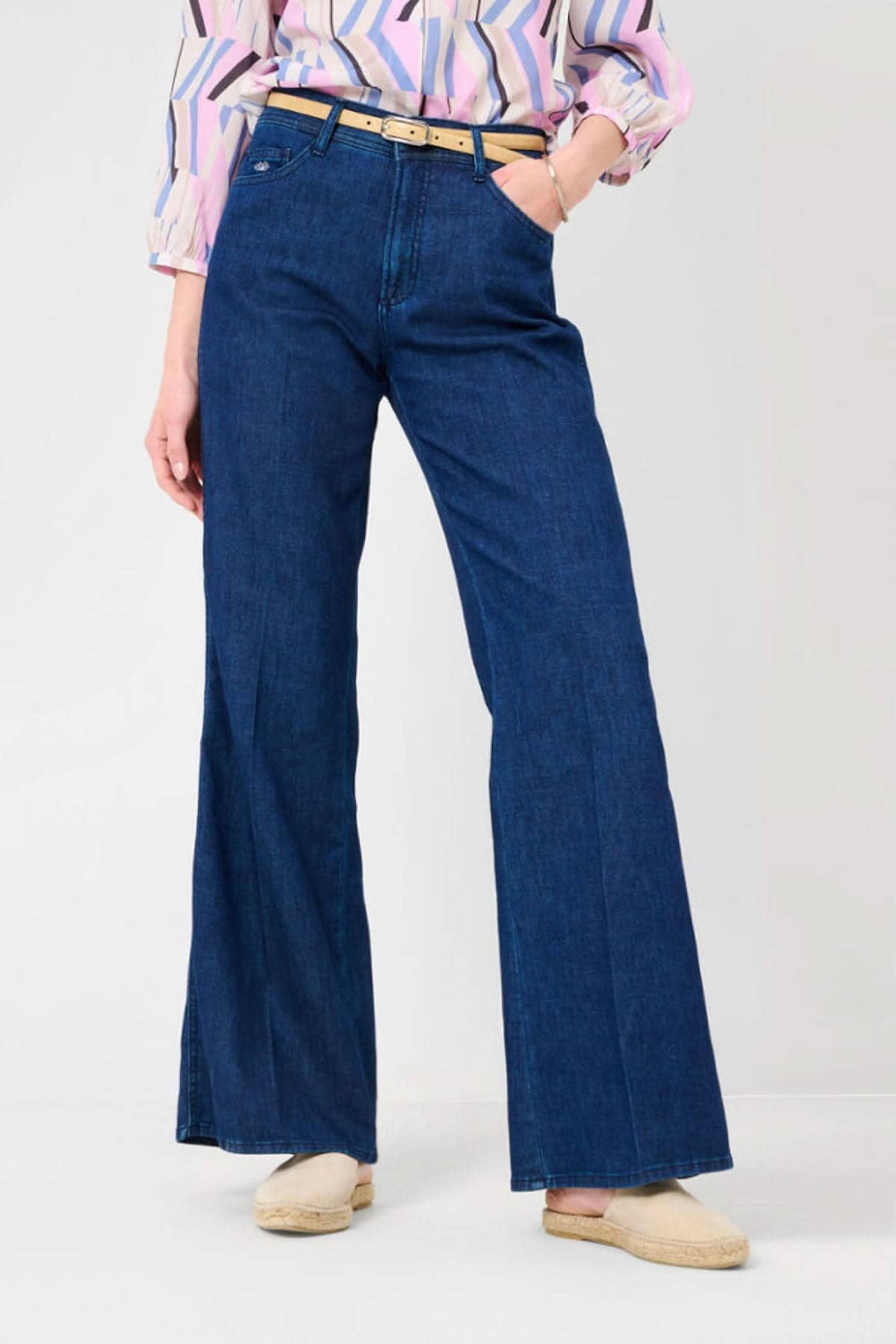 Jeans MAINE, en denim durable, coupe évasée, porté avec une ceinture et un haut coloré.