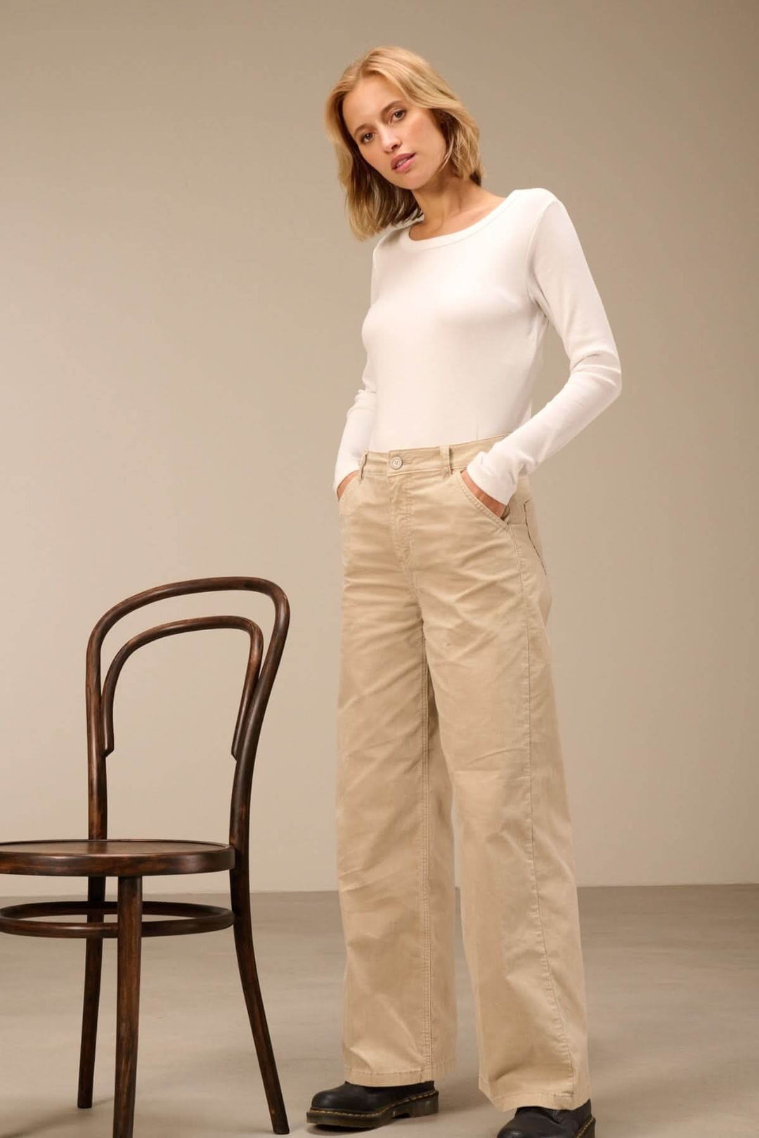 Pantalon large taille haute beige porté avec un chandail blanc, mettant en valeur le confort et l'élégance d'une coupe moderne.