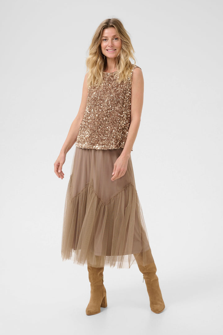 Camisole Palia en sequins, associée à une jupe fluide et des bottes, pour un look chic festif.