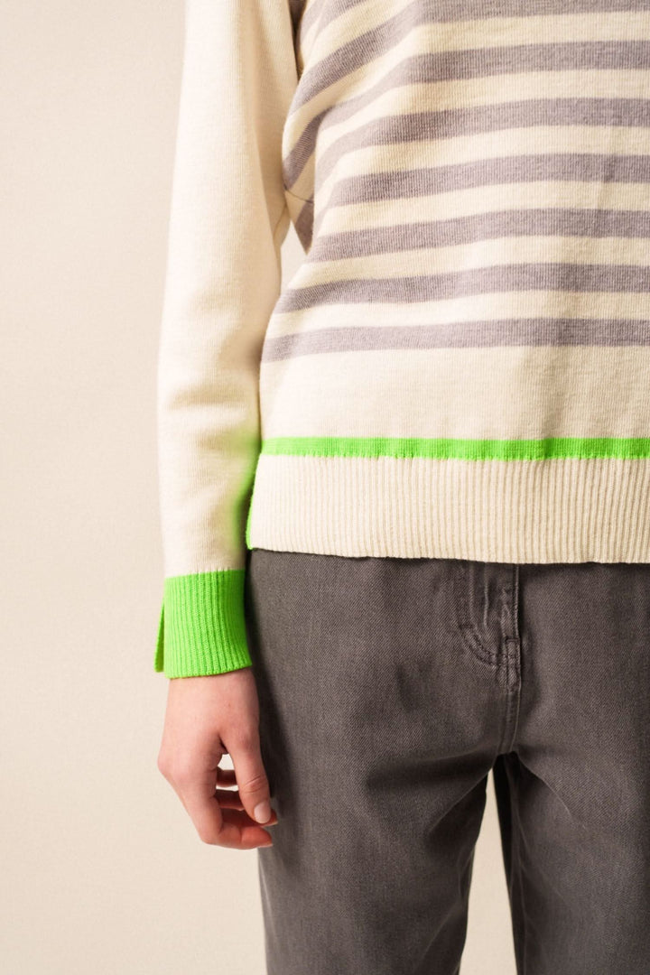 Chandail Evian rayé avec finitions fluo, porté avec un pantalon gris, pour un look moderne et décontracté.