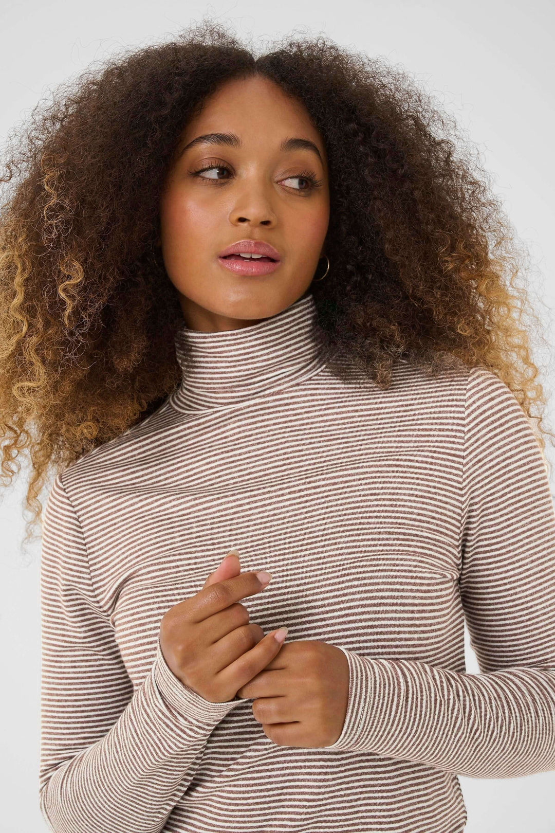 Femme portant un Chandail Amma à col roulé rayé ajusté, élégant et moderne, avec motif à fines rayures, idéal pour un look décontracté chic.