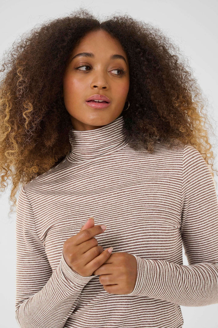 Femme portant un Chandail Amma à col roulé rayé ajusté, élégant et moderne, avec motif à fines rayures, idéal pour un look décontracté chic.