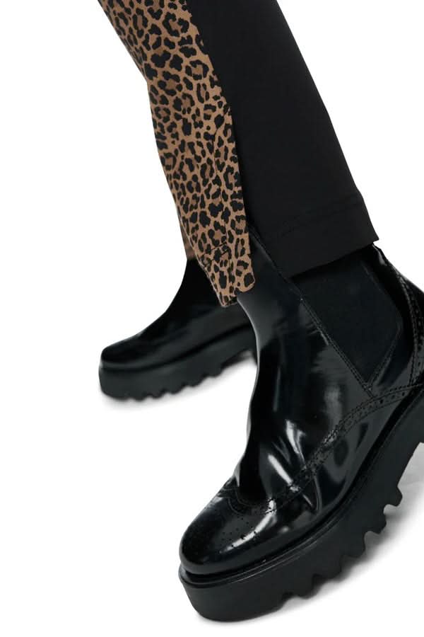 Pantalon ajusté avec imprimé animalier et bandes unies latérales, porté avec chaussures noires brillantes.
