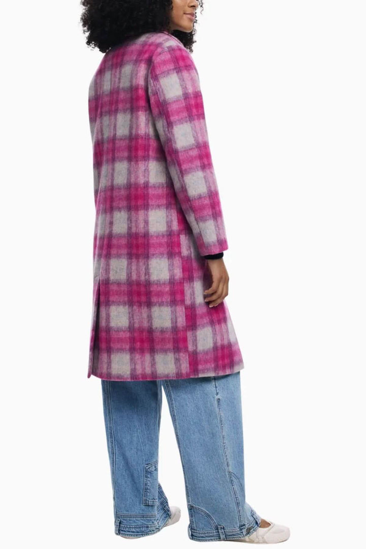 Manteau long à carreaux rose et blanc, coupe droite élégante, porté par une femme avec un jean pour un look moderne et audacieux.
