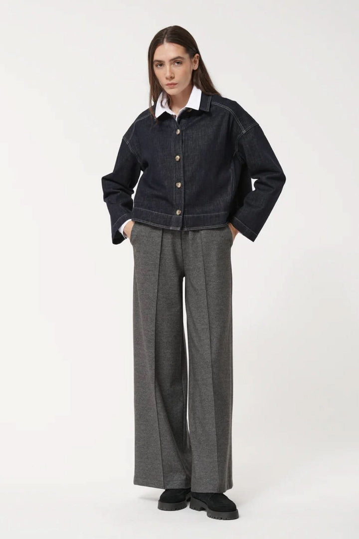 Modèle portant un pantalon ample à la coupe fluide avec taille élastiquée, plis marqués et poches latérales, pour une allure décontractée.