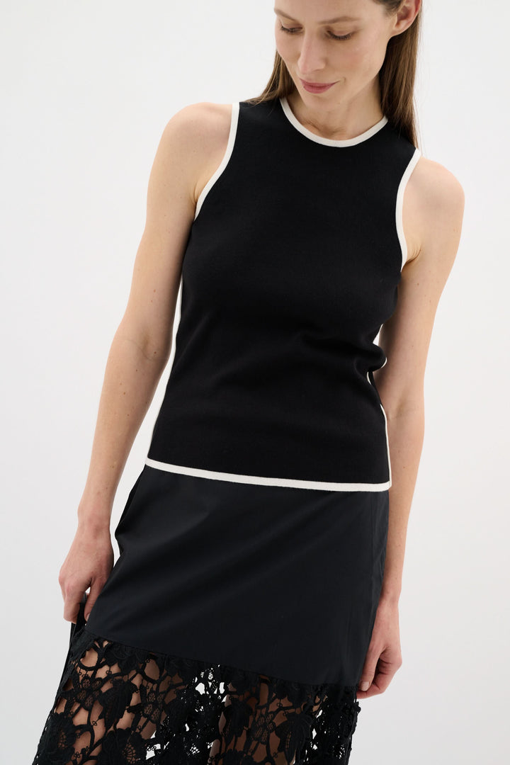 Camisole noire sans manches avec encolure ronde et liseré contrastant, style minimaliste et raffiné.