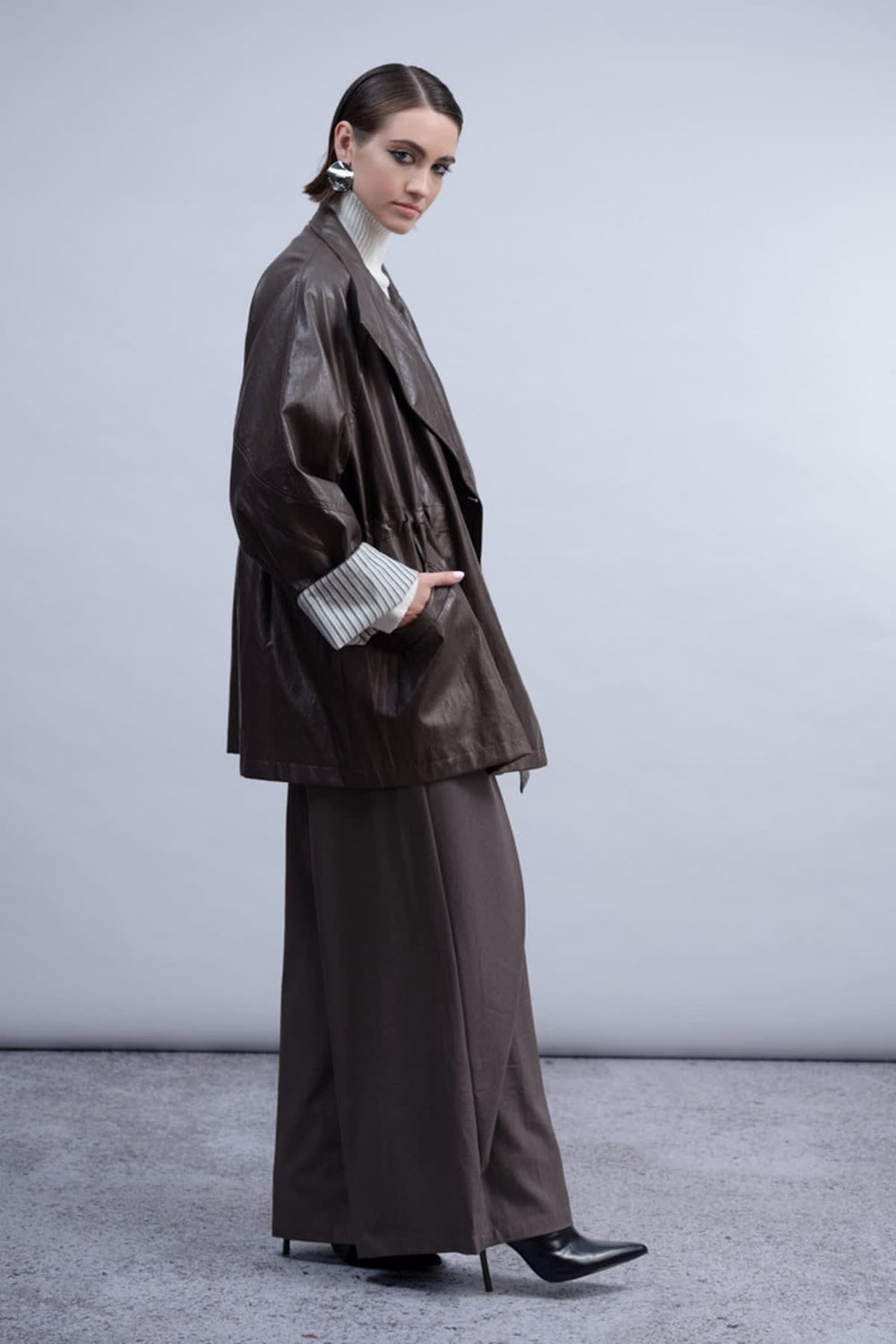 Side view of the Haako black faux leather coat for women with visible buttons - Valérie Simon