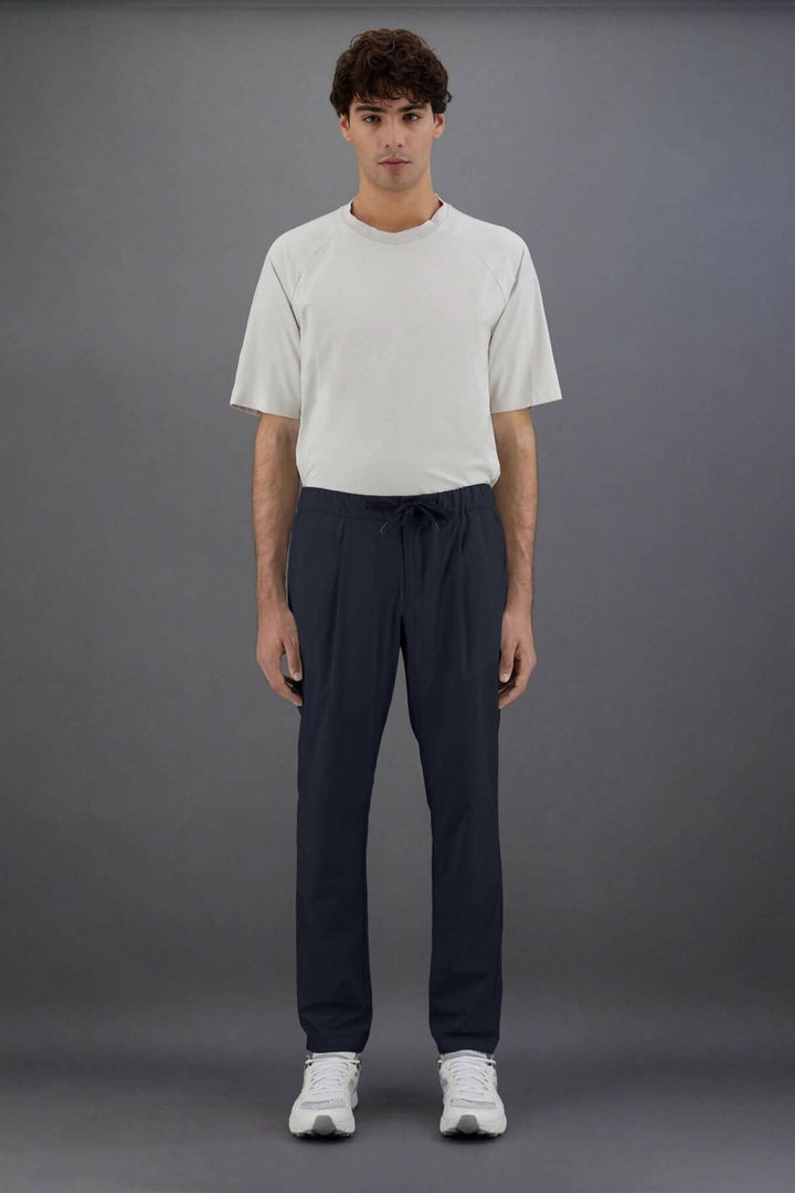 Homme portant un pantalon Laminar en nylon, style sportif et sophistiqué, avec t-shirt assorti.