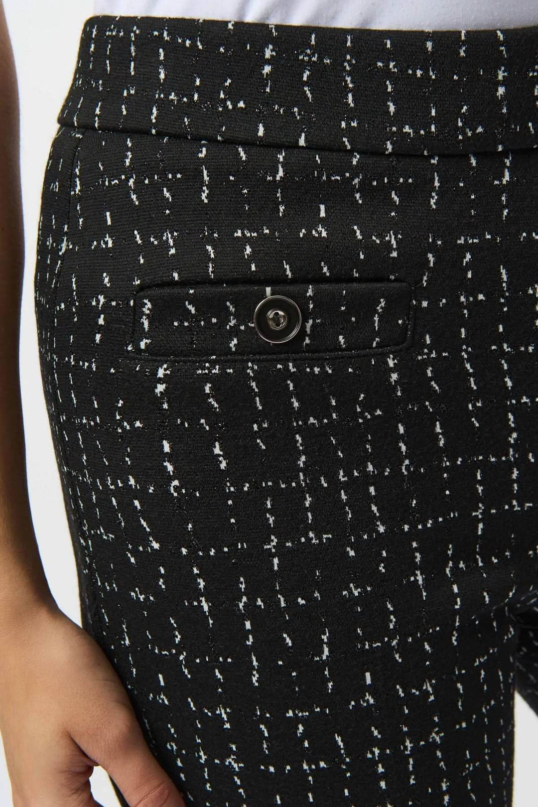 Détail du pantalon évasé noir avec motif quadrillé blanc et fausse poche à rabat.