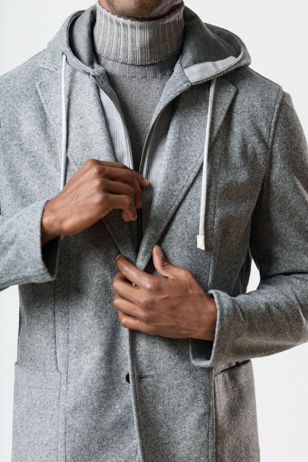 Homme portant un veston hybride à capuche en laine foulée grise, avec col roulé gris, style urbain élégant.