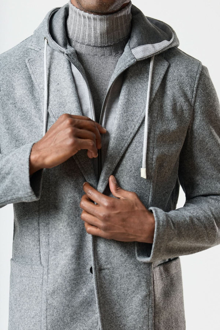 Homme portant un veston hybride à capuche en laine foulée grise, avec col roulé gris, style urbain élégant.