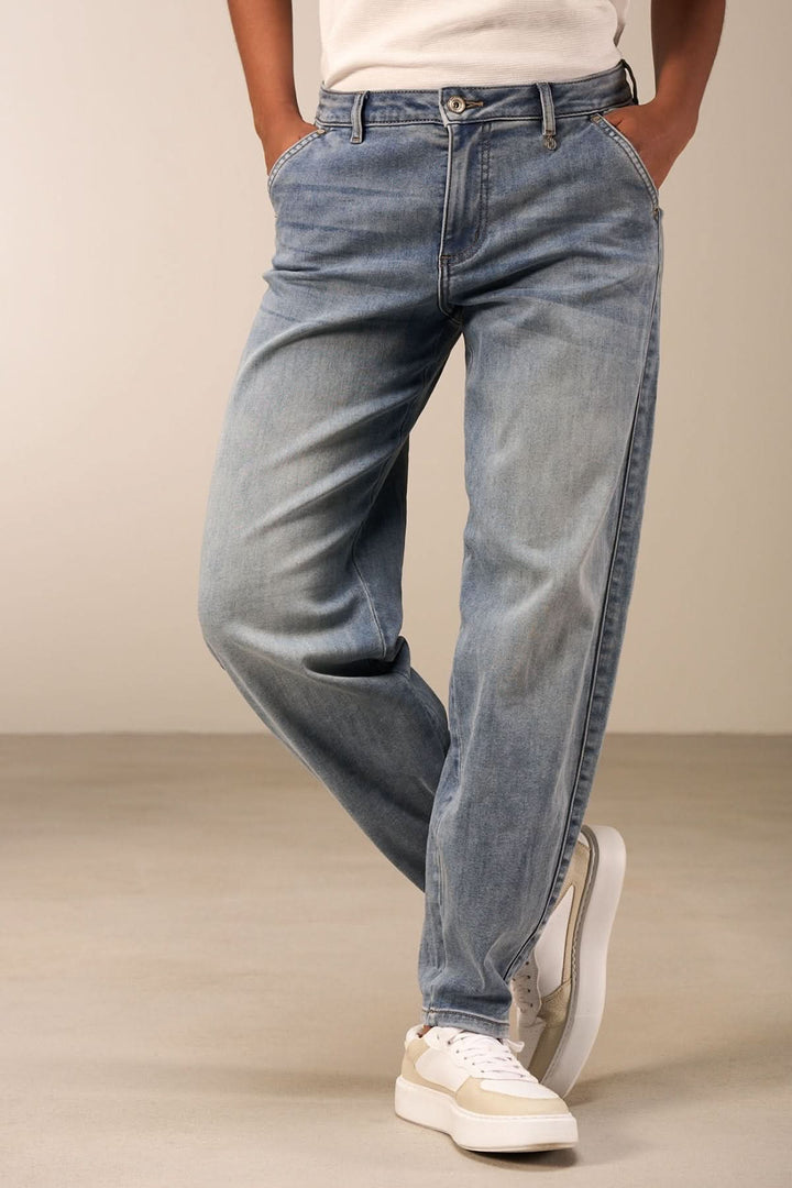 Jean coupe droite délavé avec taille mi-haute, porté avec un t-shirt blanc et des baskets blanches.