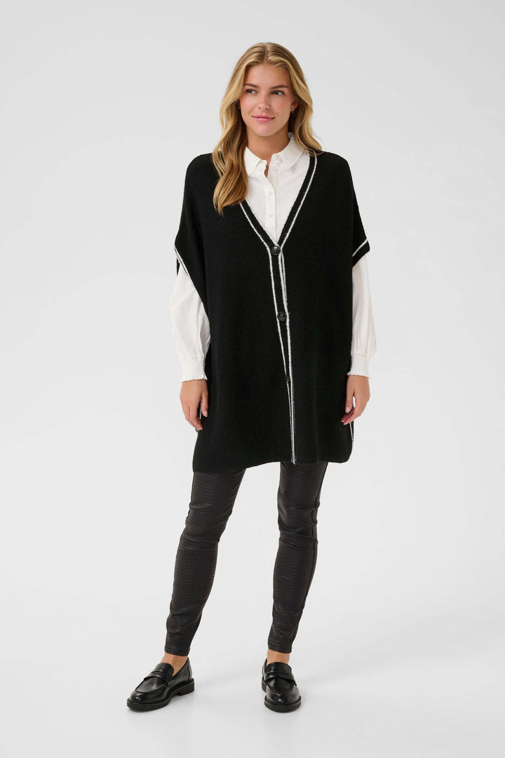 Modèle portant la Cape Rams boutonnée en tricot à bord contrastant, élégante et chic pour un style moderne et raffiné en hiver.