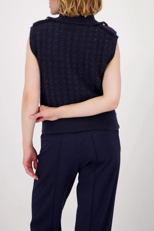 Femme portant une veste sans manches zippée en maille texturée, vue de dos, avec col montant et design moderne.