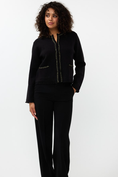 Cardigan chic noir porté avec un pantalon noir, alliant élégance et confort pour un look professionnel.