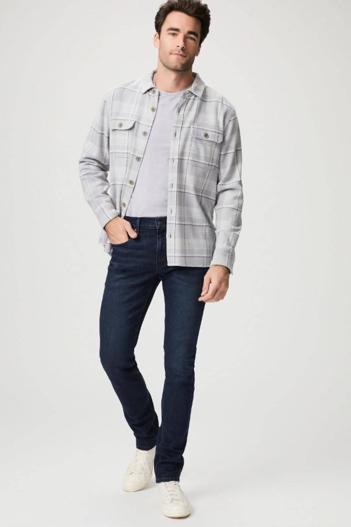 Homme portant une chemise à carreaux avec un t-shirt et un jean slim indigo, affichant un look décontracté et élégant.
