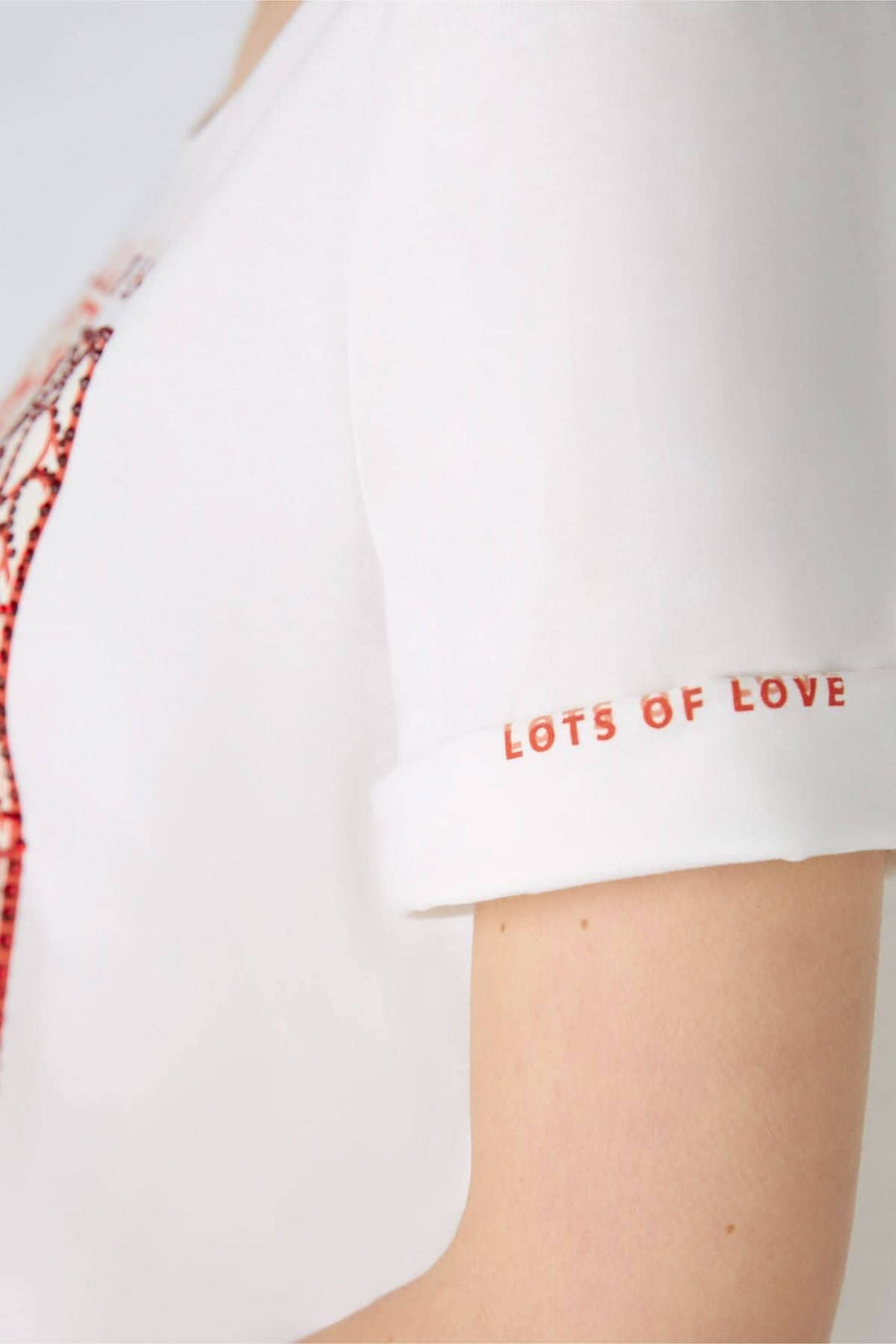 T-shirt blanc avec imprimé coloré sur le devant et texte 'LOTS OF LOVE' sur les manches courtes