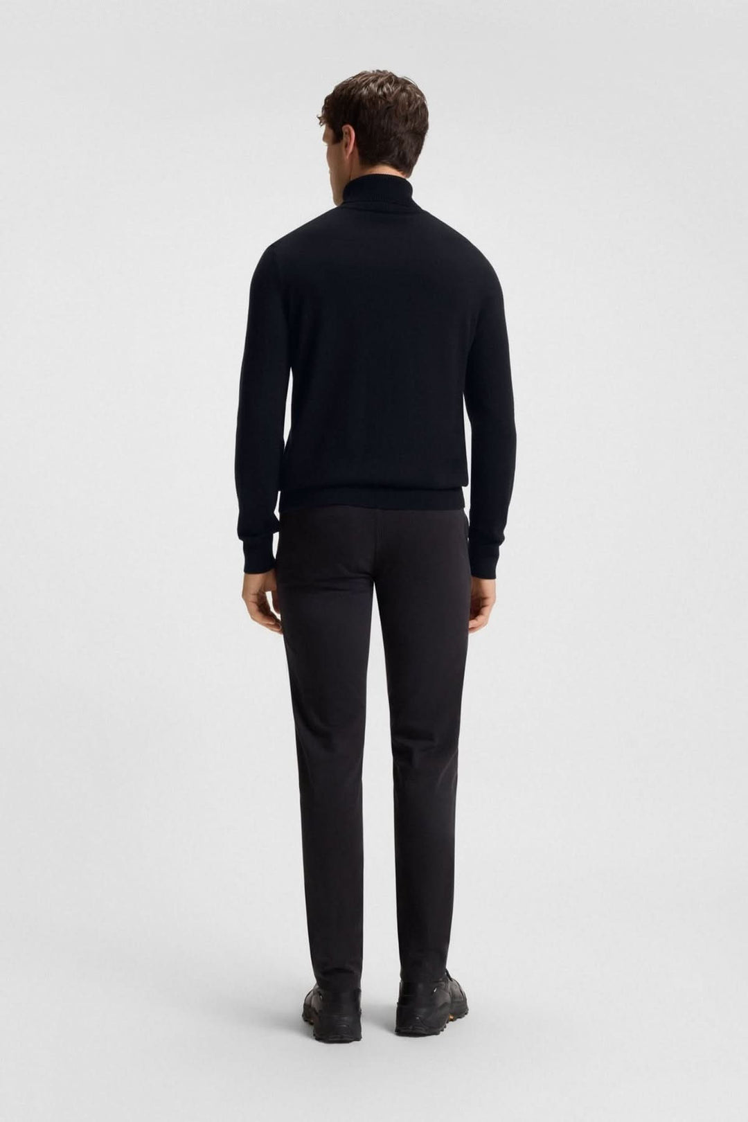 Homme portant un col roulé coton et cachemire Boss Orange noir avec pantalons habillés, vue de dos pour un look élégant et moderne.