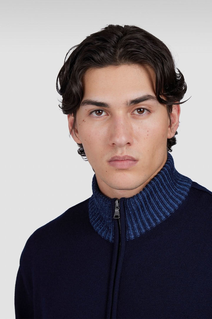Homme portant un cardigan à fermeture éclair avec col en tricot bleu, mettant en valeur une allure contemporaine.