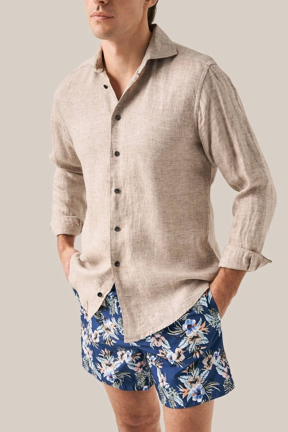Homme portant une chemise en lin et un maillot de bain fleuri à motifs dans un style décontracté.