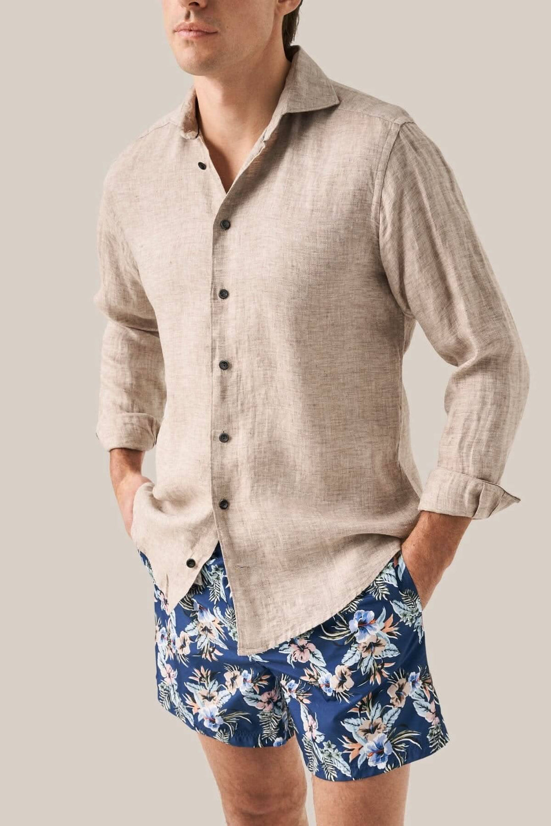 Homme portant une chemise en lin et un maillot de bain fleuri à motifs dans un style décontracté.