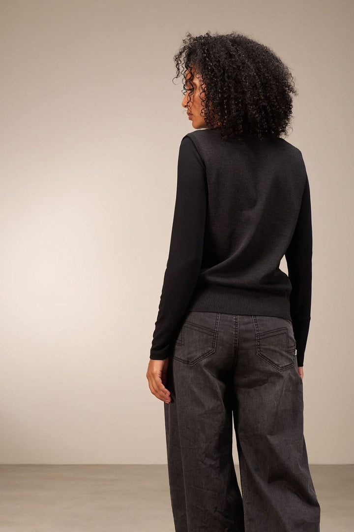 Veste sans manches noire vue de dos, associée à un pantalon large, style chic et polyvalent.