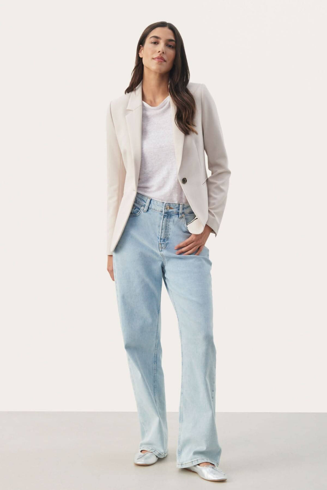 Femme portant un veston souple Taylor beige sur un t-shirt blanc avec un jean décontracté pour un look chic.