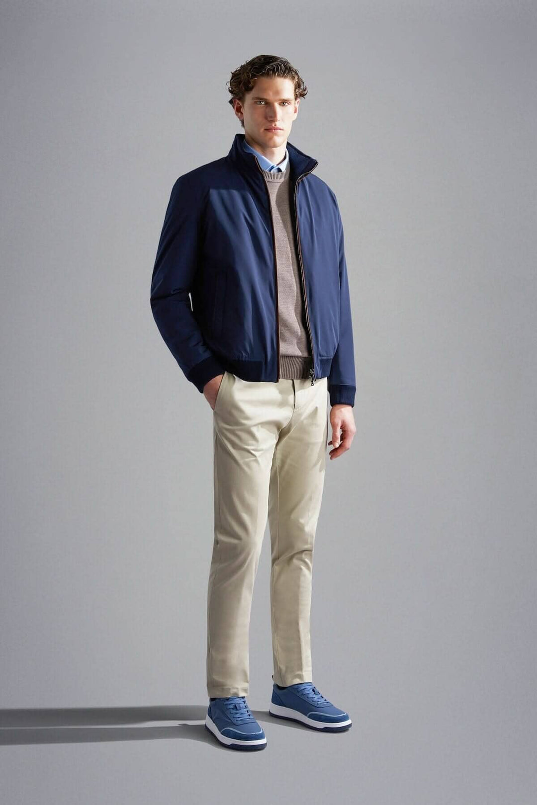 Homme en veste doublée d'automne navy avec pantalons clairs et chaussures bleues, style moderne et décontracté.