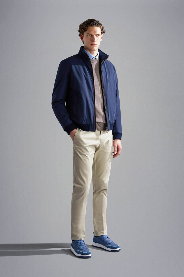 Homme en veste doublée d'automne navy avec pantalons clairs et chaussures bleues, style moderne et décontracté.