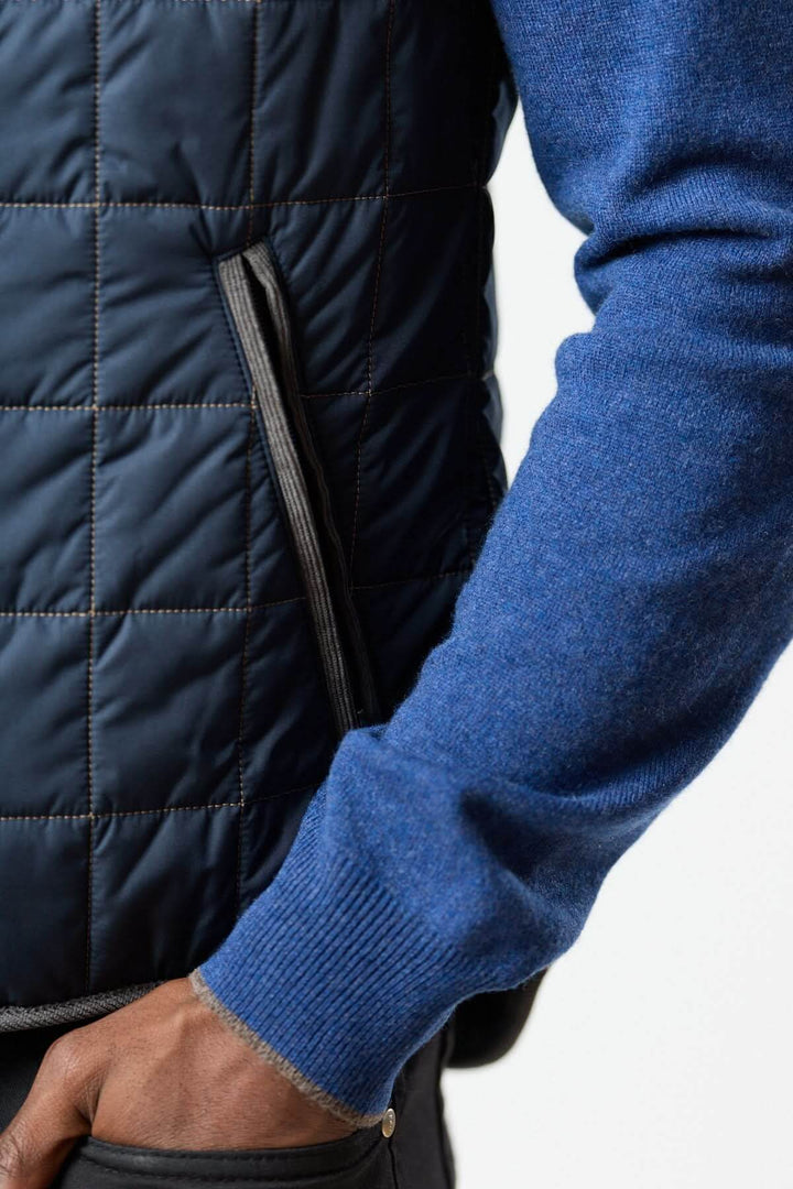 Veste sans manches matelassée avec détails en velours côtelé stylée, montrée sur fond bleu pour un look chic et décontracté.