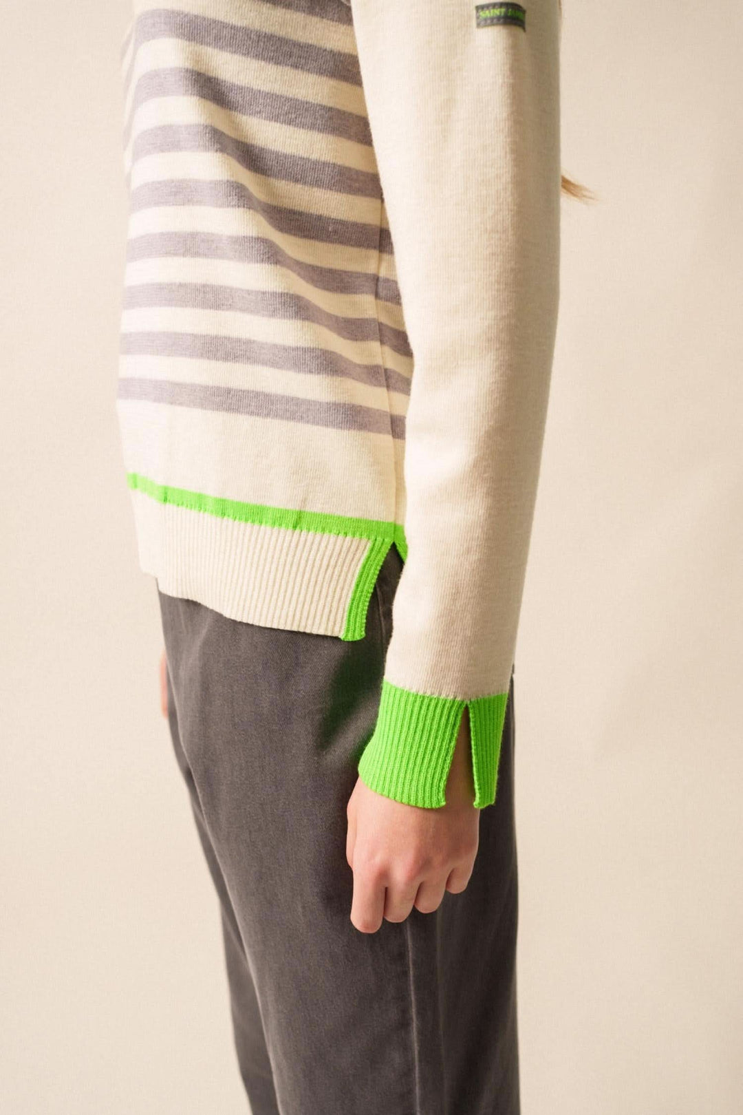 Chandail Evian avec rayures grises et finitions fluo vertes, style moderne et décontracté.