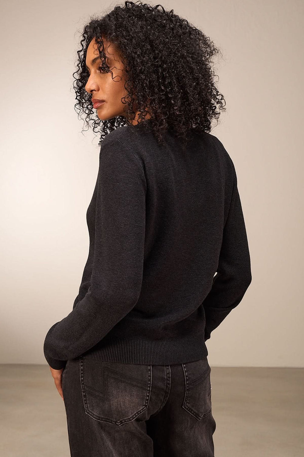 Femme portant un cardigan simple à manches longues, vue arrière, avec texture douce et coupe élégante.