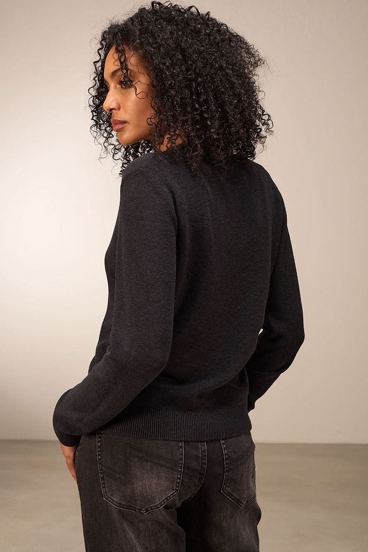 Femme portant un cardigan simple à manches longues, vue arrière, avec texture douce et coupe élégante.