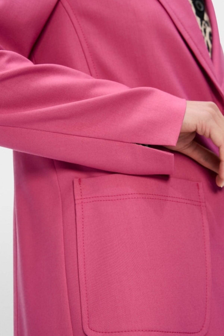 Détail d'un veston à coupe étroite rose avec poche plaquée, mettant en valeur son élégance et sa finition.