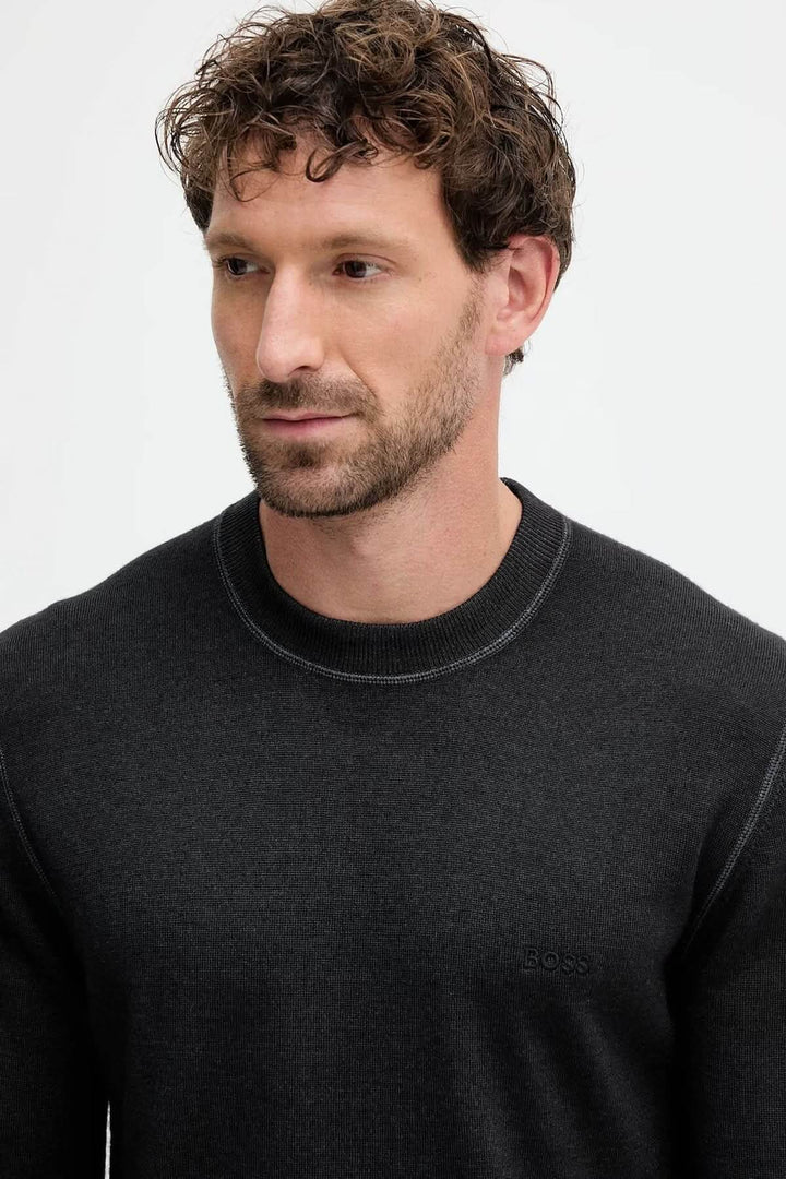 Homme portant un Chandail en laine vierge à col rond de la collection BOSS Orange, couleur sombre, cote légère, douce et confortable.