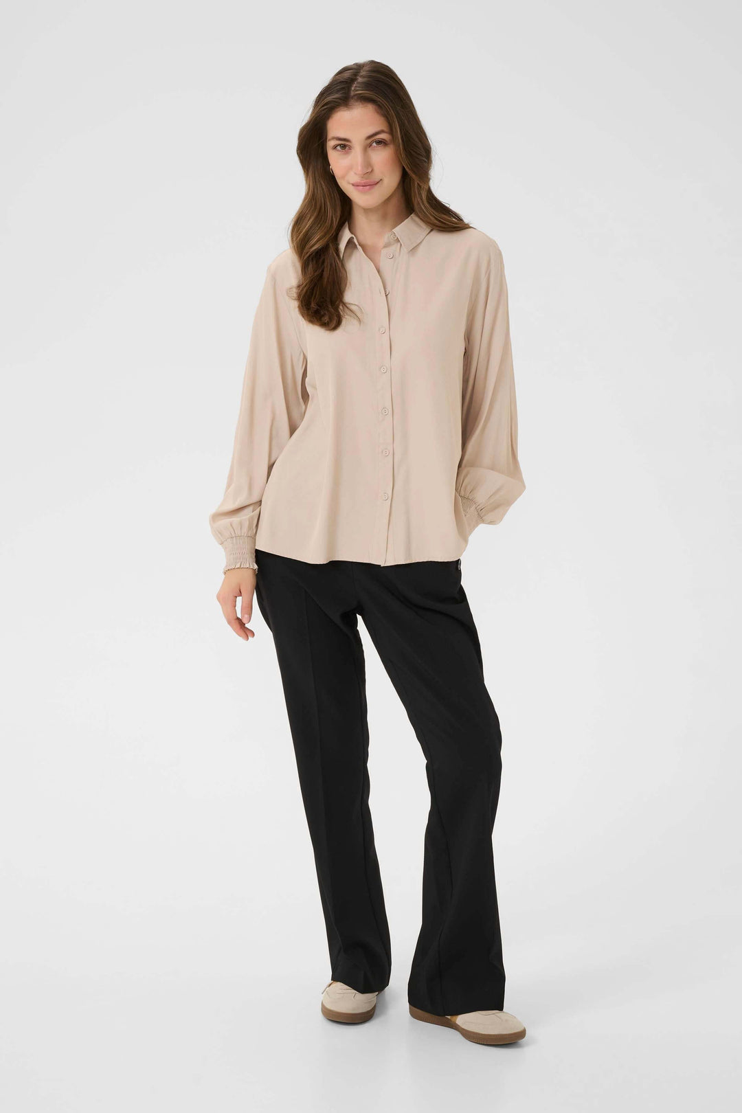 Femme portant Blouse Nola fluide à poignets smockés, look élégant et décontracté, tenue adaptée au travail et aux week-ends.