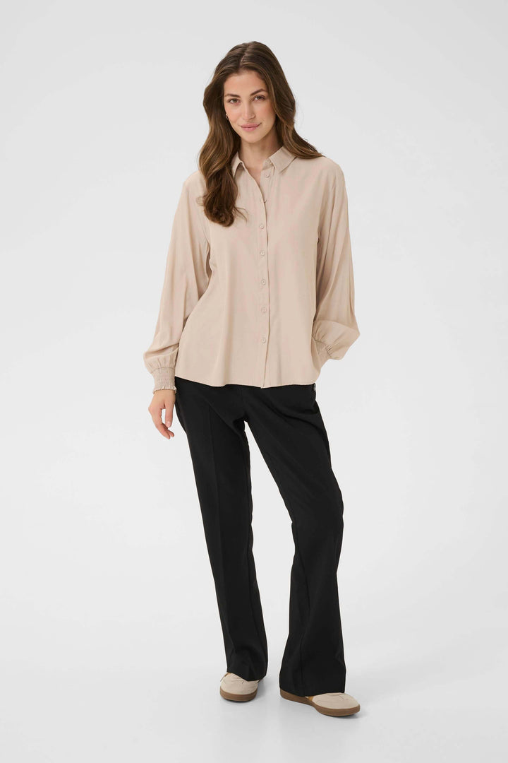 Femme portant Blouse Nola fluide à poignets smockés, look élégant et décontracté, tenue adaptée au travail et aux week-ends.