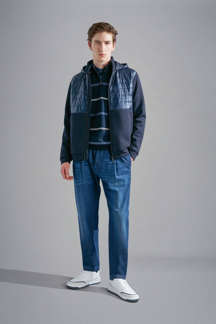 Homme portant un chandail ligné à demi-zip avec une veste et un pantalon jeans décontracté.