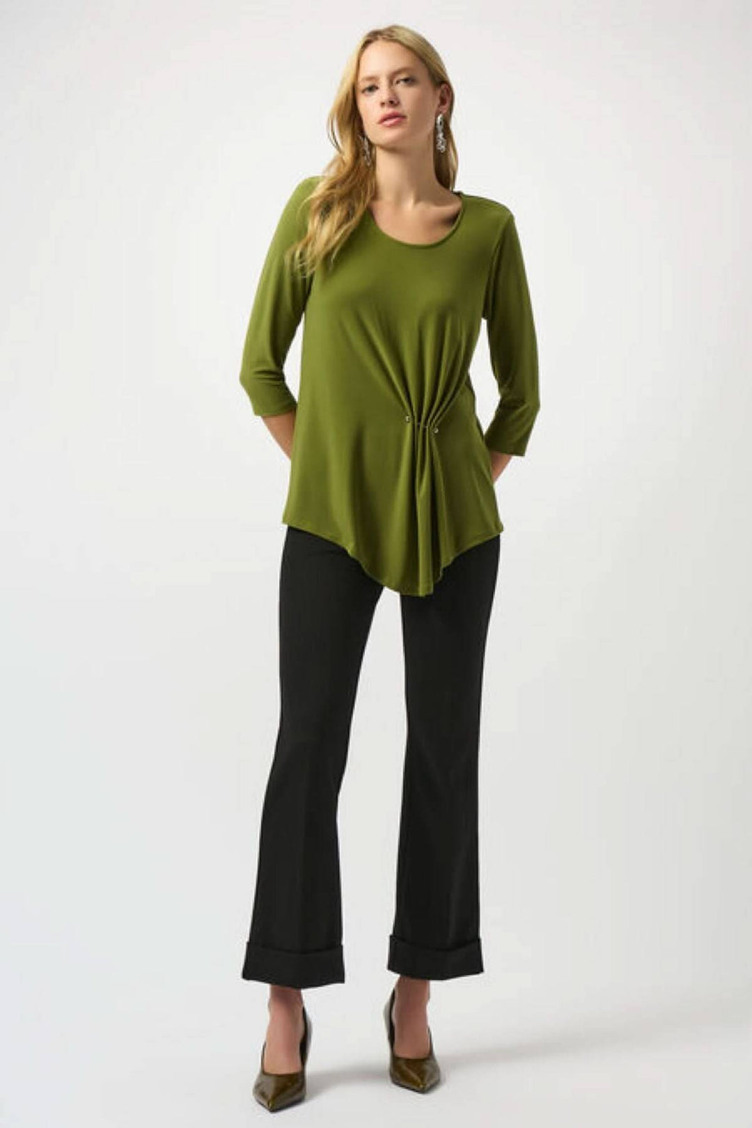 Femme portant un haut vert olive et un pantalon noir évasé, montrant un style élégant et décontracté.